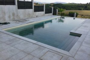 piscina in cemento armato a sfioro pietra e resina